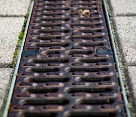 A gloved hand places a paver into place around a in-set ground drain