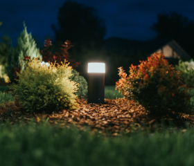 Lamps light up a lawn space with bushes